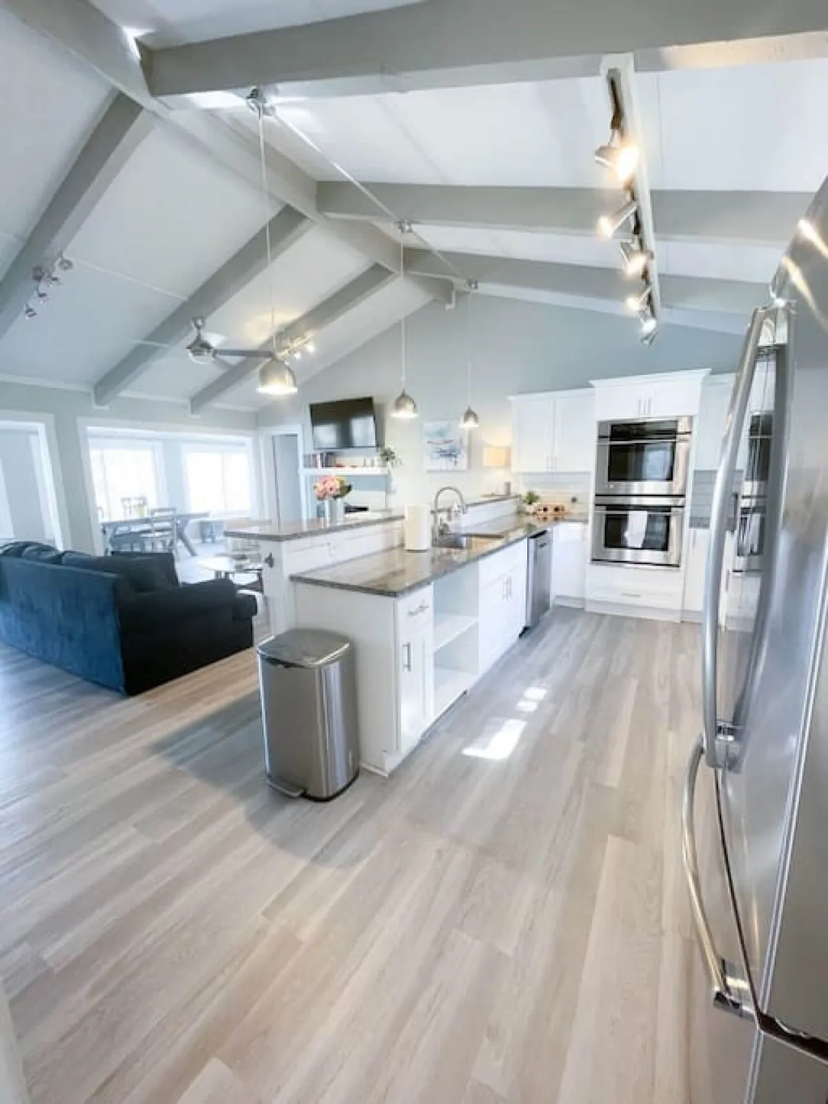 A warm, open-concept kitchen and living space with a prominent kitchen island, stainless steel appliances, and plenty of space for family gatherings or entertaining. The area is bathed in natural light and seamlessly connects to the adjacent living room.